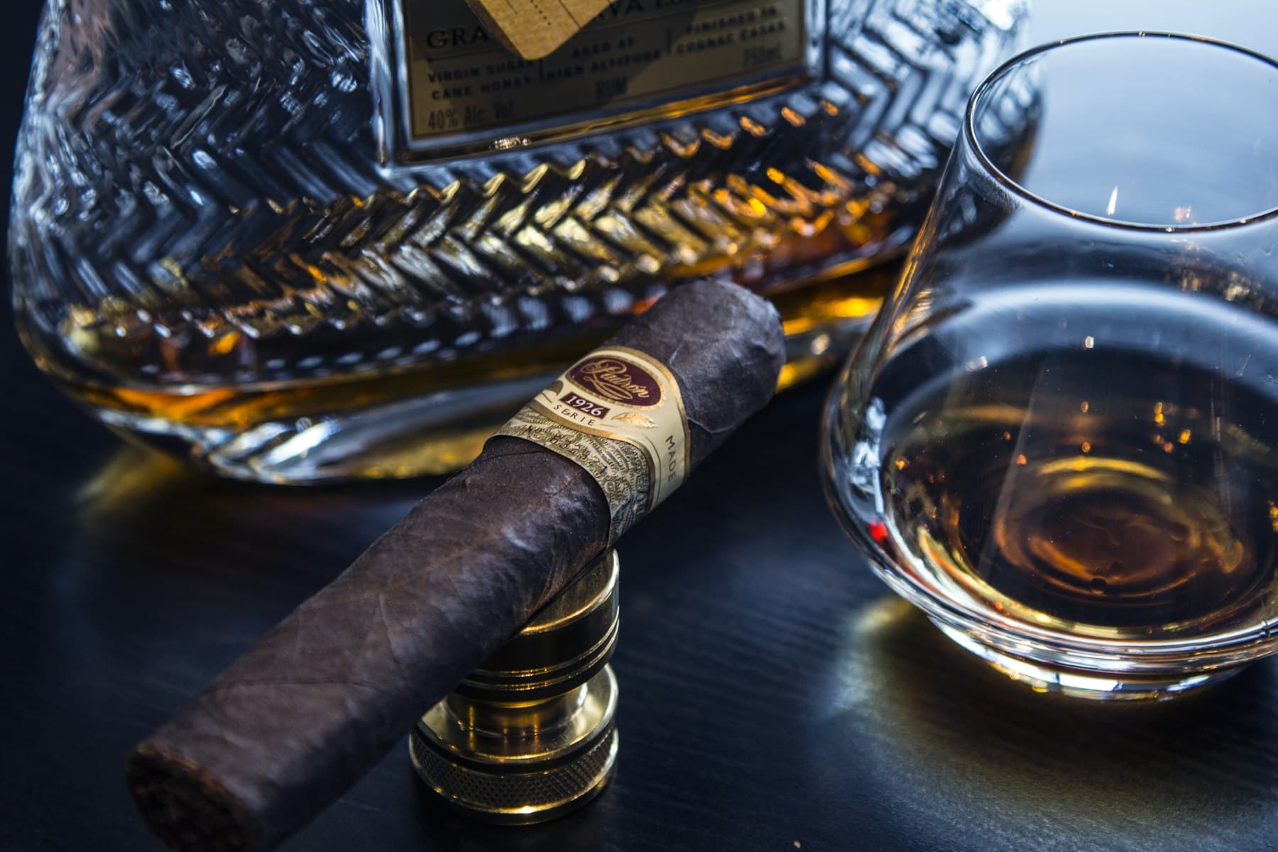 A cigar resting beside a glass of amber spirit